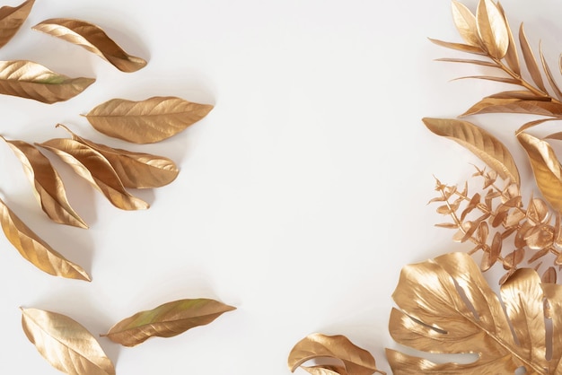 Gold tropical palm leaves Monstera on white background Flat lay