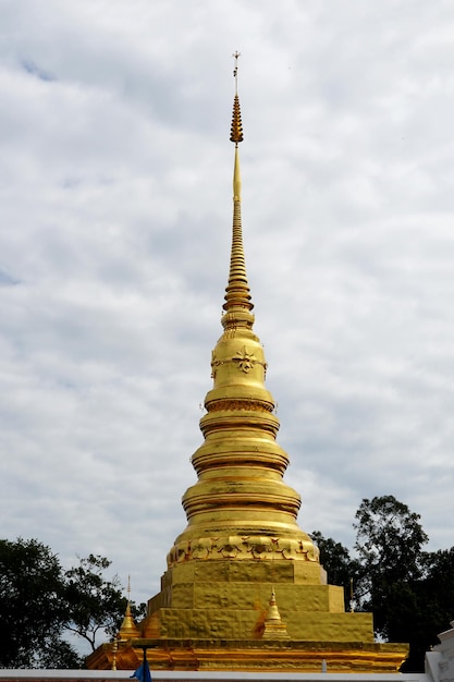 The goldcolored chedi on clouds in the sky background of Wat Phra That Chae HaengNan Thailand