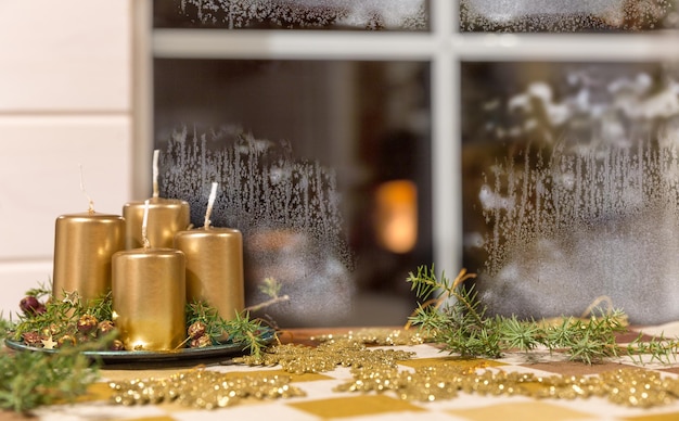 Golden Advent candles on a table in front of a window in winter weather hoarfrost