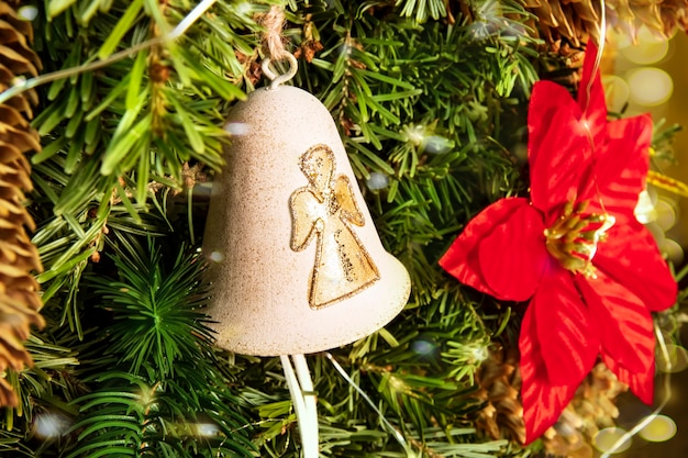 Golden bell with a Christmas angel on a traditionally decorated tree with a Christmas star and bokeh