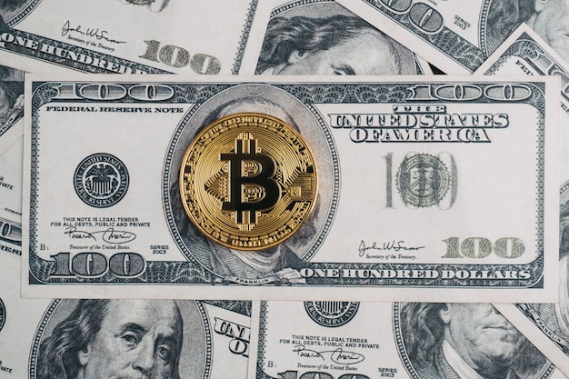 Golden bitcoin on top of dollar bill and dollar banknote background