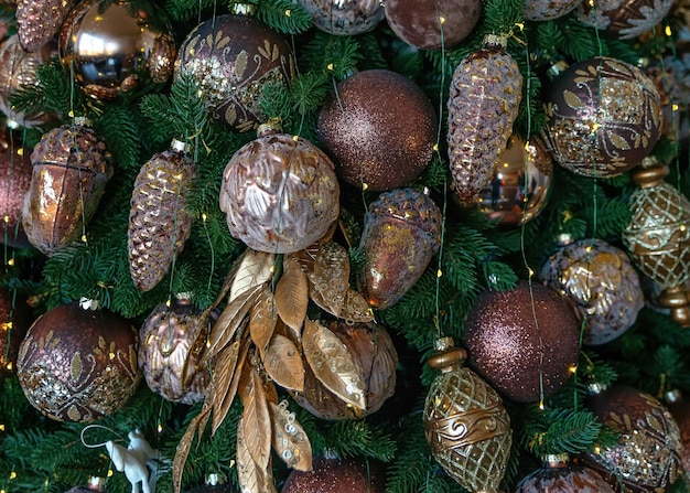 Golden and bronze toys on the fir tree close up Background with Christmas decorations