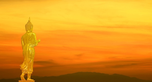 Golden Buddha Image on Gradient Orange Color Sunrise Sky over the Mountains