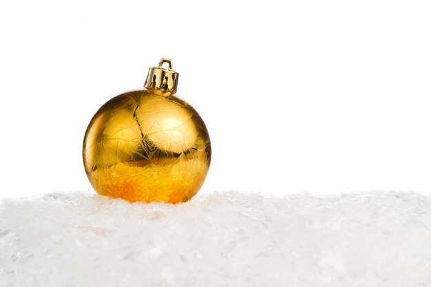 Golden Christmas ball on snow isolated on white background with