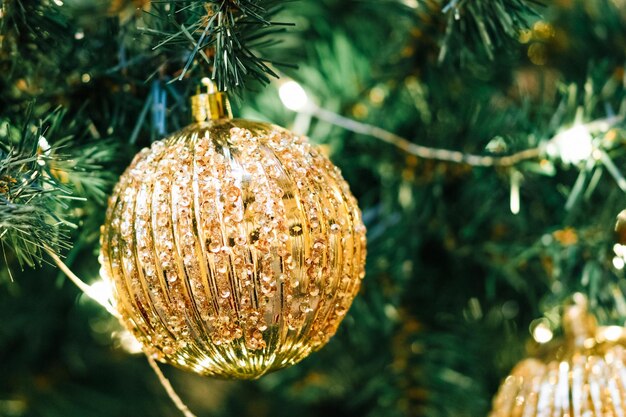 Golden Christmas ball with sparkles and garlands on a Christmas tree closeup