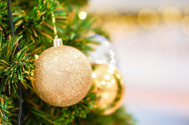 Golden Christmas Balls Decorated on Pine Tree on Christmas day with blurry background and bokeh of Christmas lighting.