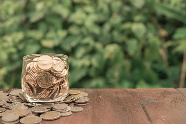 Golden coins in glass on wood backgroundsaving money concept