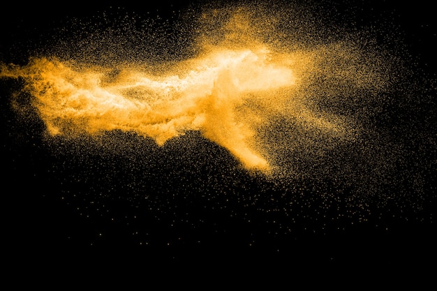 Golden colored sand splash against dark background. 