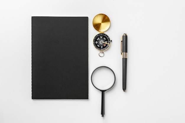 Golden compass with black notepad and pen close up on a table