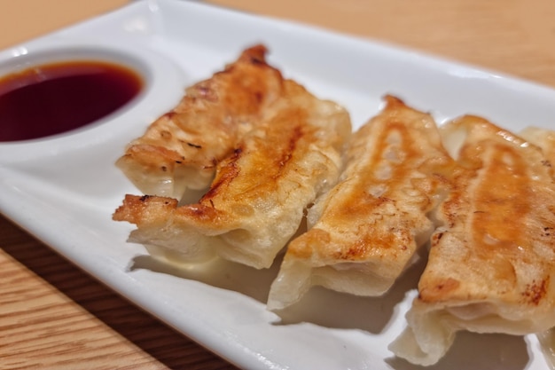 Golden crispy fried gyoza grouped on wooden floor