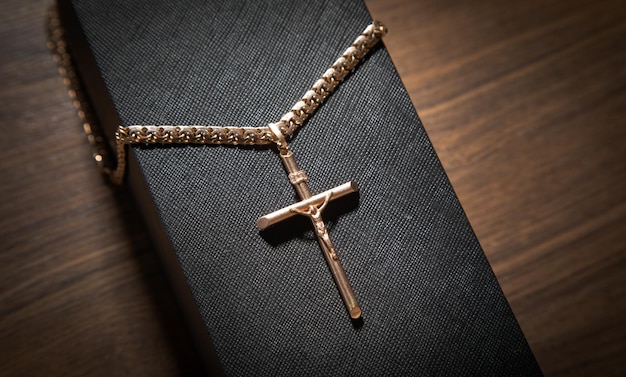 Golden cross necklace on wooden background