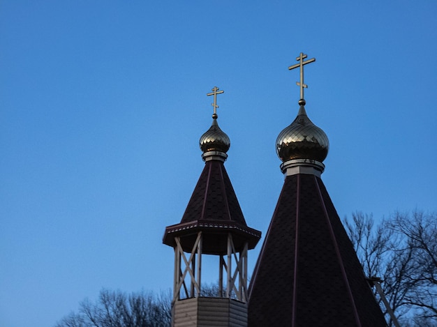 The golden domes of an Orthodox wooden church against the sky