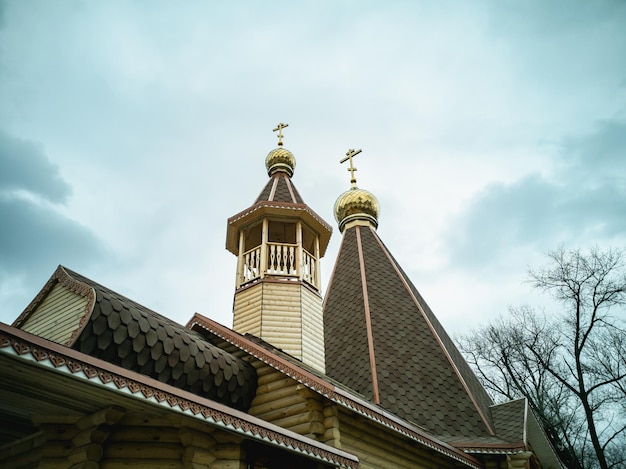 The golden domes of an Orthodox wooden church against the sky