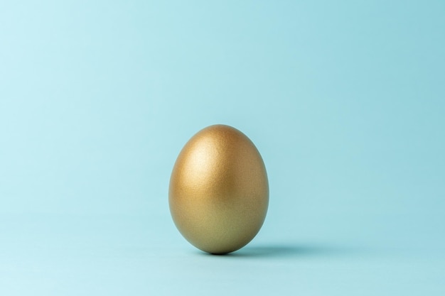 Golden Easter egg on blue background Easter minimal concept