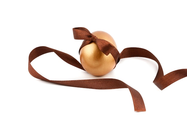 The golden Easter egg is decorated with a bow and curly ribbon