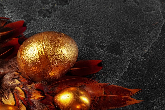 Golden Easter eggs on red bird feathers close up