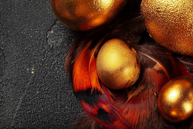 Golden Easter eggs on red bird feathers close up