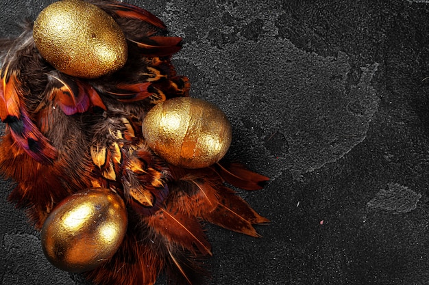 Golden Easter eggs on red bird feathers close up