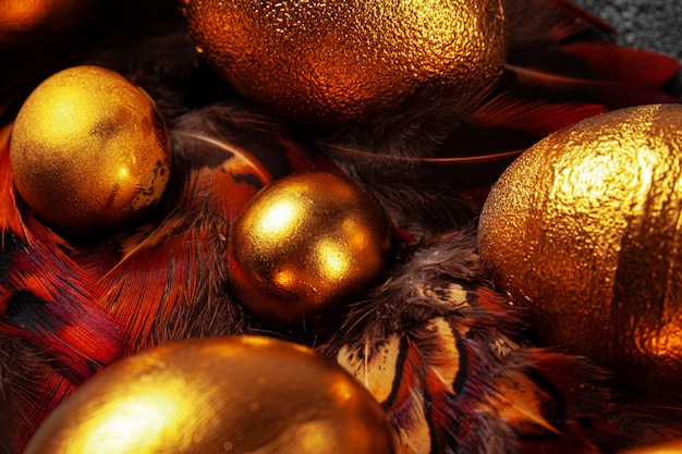 Golden Easter eggs on red bird feathers close up