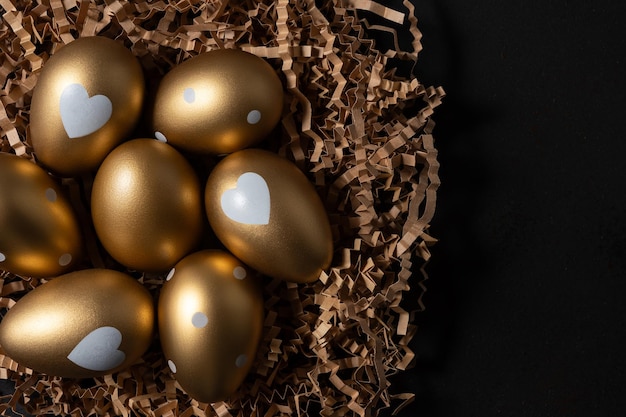 Golden eggs in paper nest on dark table