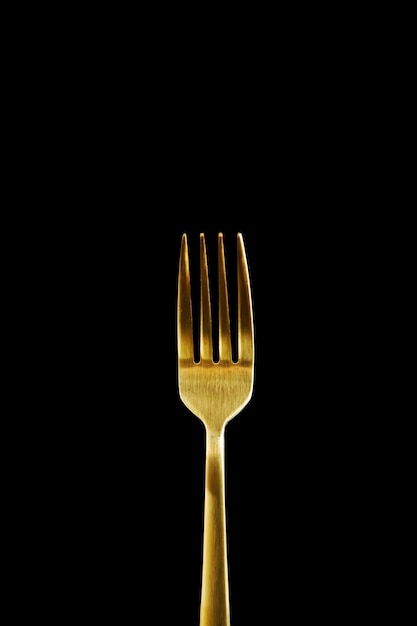 Photo golden fork isolated on black background closeup of a fork with copy space