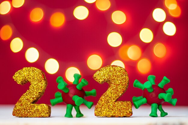 Photo golden glittering numbers 2020 with covid-19 virus with bokeh on red background. copy space.