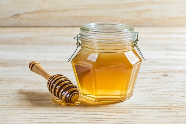 Golden Honey in a Glass Jar with Wooden Dipper