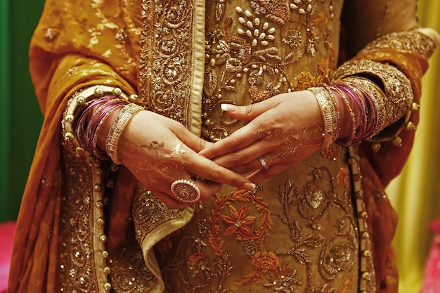 golden jewelry bracelets and rings in woman's hands with henna