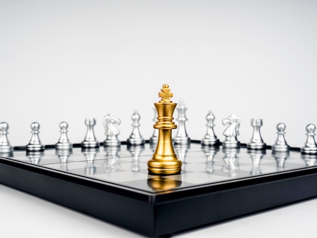 The Golden king chess piece standing on chessboard corner in front of many silver chess pieces on white background Leadership fighter competition confrontation and business strategy concept