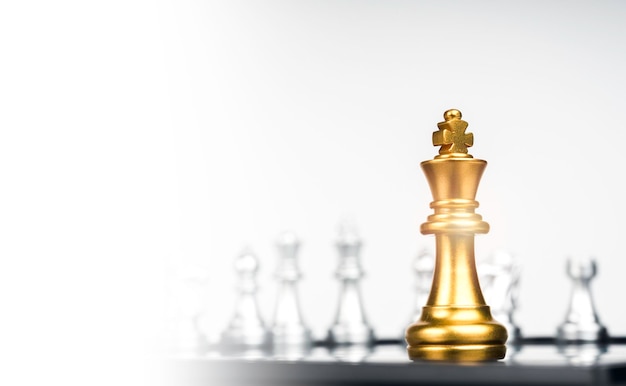 The Golden king chess piece standing on chessboard in front of silver chess pieces on white background with copy space Leadership fighter competition confrontation and business strategy concept