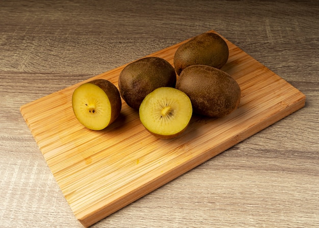 Golden kiwi whole and slices on wooden table, healthy food and fruit concept