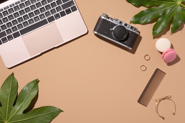 Photo golden laptop on beige background with green leaves. beauty woman blog. top view, flat lay. home office desk.