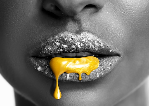 Golden lipstick dripping from sexy lips of beautiful model girl.