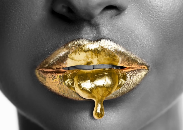 Golden lipstick dripping from sexy lips of beautiful model girl.