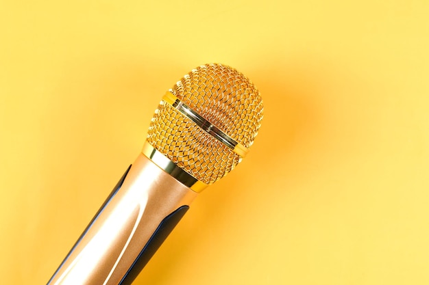 Golden microphone isolated on yellow background close upxA