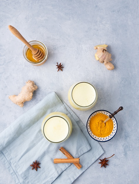 Golden milk with turmeric and honey on blue background