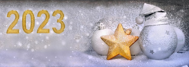 Golden new year 2023 next to christmas decoration covered with artificial snow