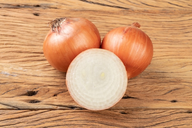 Golden onions and half onion over wooden table.