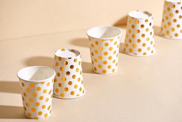 Golden polka dot paper cup isolated on beige background