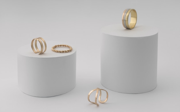 Golden rings collection on white cylinders paper platforms