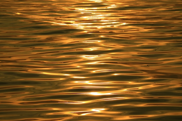 Golden ripples of the sea water surface dazzling in the morning sunlight