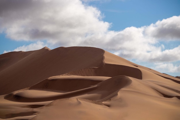 Golden sand dune 7 and white clouds on a sunny day in the Namib desert. Fantastic place for travelers and photographers