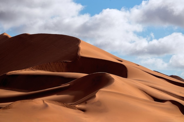 Golden sand dune 7 and white clouds on a sunny day in the Namib desert. Fantastic place for travelers and photographers