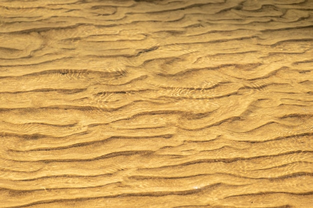 Golden sand under water during sunset as background