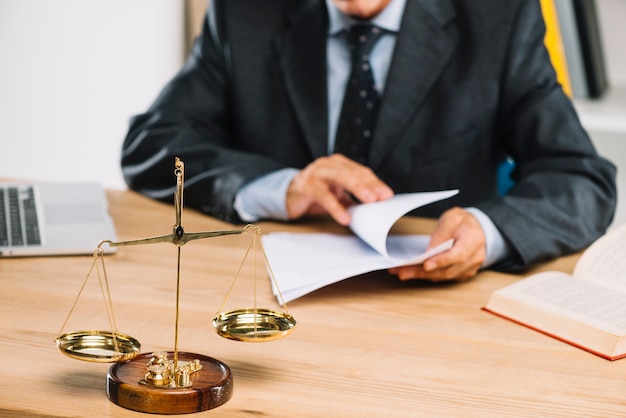 Golden scale justice in front of lawyer turning document pages in the court room