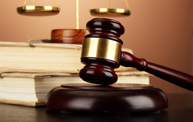 Golden scales of justice gavel and books on brown background