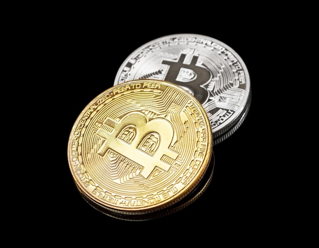 Golden and silver metal bitcoin on a black background