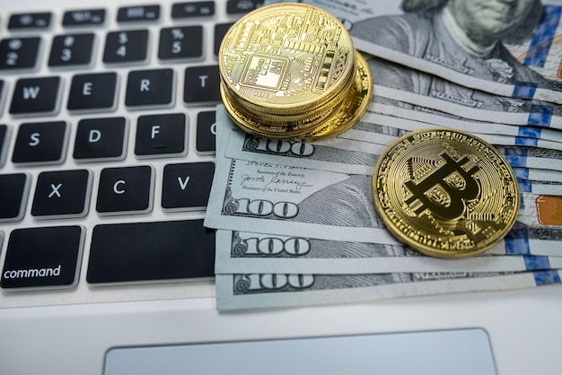 Golden souvenir bitcoin with dollar bills on laptop keyboard isolated on black background