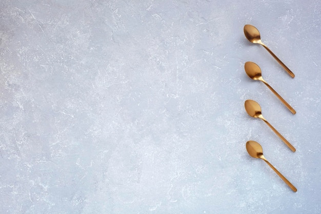 Golden spoons on grey background flatlay space for creating a list or plan