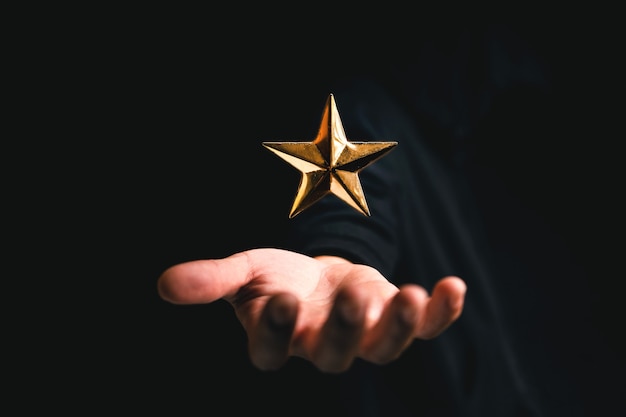 Golden star rating on hand in dark background,rating